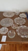 Table display of all glass platters and serving bowls showing variety in size and design.