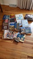 Photo of various books and magazines arranged on a hardwood floor, including titles on gardening, religion, history, art, and several magazines.