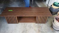 Full view of vintage wooden coffee table showing slatted wooden detail on one side, lower shelf, and long rectangular shape.