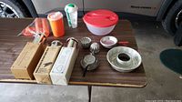 Table with all items laid out showing Tupperware items, baking tubes, molds, pans, and waffle maker