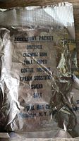 Close-up photo of a sealed WWII accessory packet listing contents such as matches, chewing gum, toilet paper, instant coffee, cream substitute, sugar, and salt.