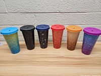 Full view of all 6 astrology-themed tumblers in a row showing their lids and constellation designs.