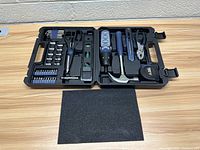 Full tool kit case open on wood surface showing all contents.