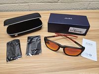 Top angle view of Jojen sunglasses with hard case, brand box, two cloth pouches, and instruction card on wood surface.