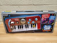 Front view of Little Tikes My Real Jam keyboard in original packaging showing keyboard keys, microphone, speaker, and control knobs.