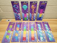 Front view of 10 Fidget Suckers in original purple packaging arranged in two rows on a wooden surface against brick wall background