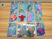Top-down view of 12 assorted bubble pop keychains on retail cards, showing shapes, colors, and attached clips.