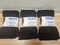 Three pairs of folded black fleece-lined leggings, labeled LukES Fleece-Lined Leggings, showing all three sizes S/M, M/L and 1X/2X.