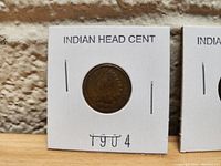 Photo of a 1904 Indian Head cent mounted in a white paper holder labeled INDIAN HEAD CENT