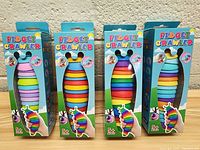 Front view of 4 new large Fidget Crawlers in blue boxes with colorful segmented bodies visible through window.