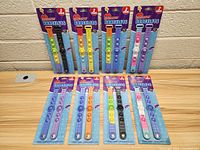 Eight packages of Bubble Pop Pop Bracelets, each package containing two silicone bubble pop bracelets in various color combinations, displayed unopened on a table.