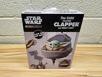 Front view of the box showing Star Wars Mandalorian branding, image of The Child in pod, clapper text and night light feature.