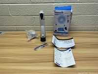 Photo showing the cordless Waterpik water flosser device, charging base, charging cable, replacement tip sealed in plastic, instruction manuals, and original box.