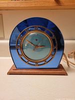 Front angle showing blue glass face, brass numerals and wood base