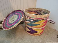 Top view of colorful woven basket with matching lid placed beside it, showing pattern details.