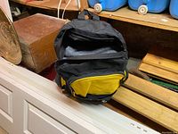 Black and yellow backpack partially open on wooden surface