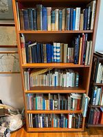 Full view of large bookshelf filled with multiple shelves of vintage books of various sizes and conditions, mostly hardcover with cloth bindings.
