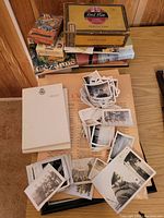 Lot overview showing books, cigar box, papers, and numerous black and white photos spread out on a table