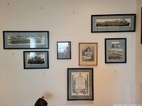 Wide view of six framed military and navy themed items on wall showing group photos, certificate, and individual portrait