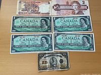 Top view showing Indian 10 Rupees note and Canadian 2 Dollar bill and four Canadian 1 Dollar bills and one Dominion of Canada 25 cents bill on bottom.