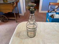 Full view of vintage glass decanter with stopper on table showing geometric line patterns.