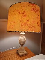Photo of full vintage onyx stone table lamp with orange-brown textured fabric shade on wooden surface