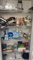 Full view of linen closet wire shelves showing towels, toiletries, candles, and health care items