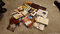 Photo showing a pile of assorted books of various genres including self-help and fiction on carpeted floor.
