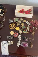 Overview of assorted costume jewelry brooches and pins arranged on table including boxed Christmas-themed set and other floral and leaf designs.