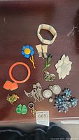 Full lot overview with bracelets, brooches, earrings, and rings laid out on a wooden surface.