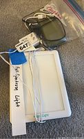 Full spectrum light panel labeled HappyLight with attached white cables and a small electronic charger/device in plastic bag.