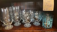 Photo of 11 glassware pieces including 8 clear glasses with textured bases and 3 blue patterned glasses