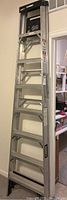 Full length view of 8ft aluminum Husky stepladder in upright position showing all steps and black rubber feet.