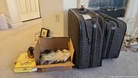 Two-piece gray textured matching luggage next to a box with assorted buttons and small decor items