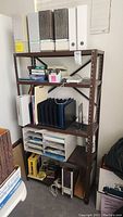 Full view of brown metal shelving unit loaded with binders, file boxes and office supplies.