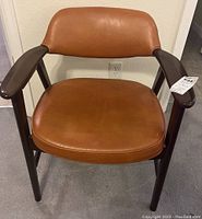 Front view of mid century brown leather and dark wood club style armchair