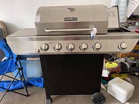 Full front view of the Nexgrill propane grill showing five burner control knobs, two side shelves, black base with wheels.