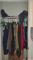 Photo showing jackets hung on hangers in closet, folded clothes and small selection of ties on shelf.