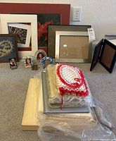 Photo of photo albums stacked on the floor, assorted picture frames behind them, and some photo mattes on the side.