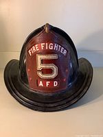 Front view showing red leather front shield marked “Fire Fighter 5 AFD” and black painted ribbed dome.