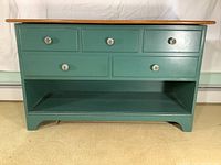 Front view of painted wooden chest with five faux drawers and ornate patterned glass knobs.