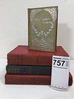 Stack of four vintage books including Uncle Tom's Cabin on top with visible ornate silver design on cover.