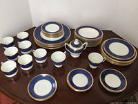 Overhead group photo displaying 50-piece incomplete Coalport Athlone Blue dinnerware set arranged on a table showing various plates, bowls, cups, sugar bowl with lid.