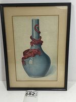 Photo of framed print showing a tall blue vase with a red dragon coiled around its neck and body. Image shows beige matting and simple black frame with glass.