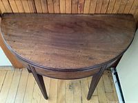 Top view of the table in closed demilune form showing wood grain and wear.