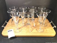 Wide image showing 11 wine glasses arranged on large oak tray with pewter handles.