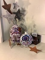 Two Royal Copenhagen vases decorated with purple and blue floral motifs, each adorned with copper and galvanized steel wire star decorations surrounding the necks.