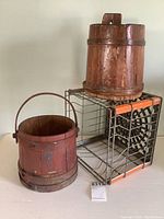 Photo showing two wooden shaker style buckets, one red and one natural wood, and the Pioneer Dairy steel wire milk crate.
