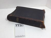 Closed book showing black leather cover with wear and gold embossed spine text