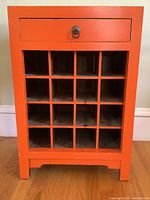 Front view of the orange side table showing the drawer and 20-slot wine rack grid.